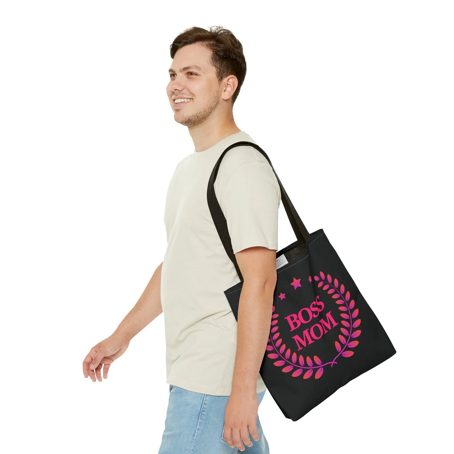 A person carrying a black tote bag that proudly boasts Boss Mom in pink lettering, embraced by a laurel wreath and stars.
