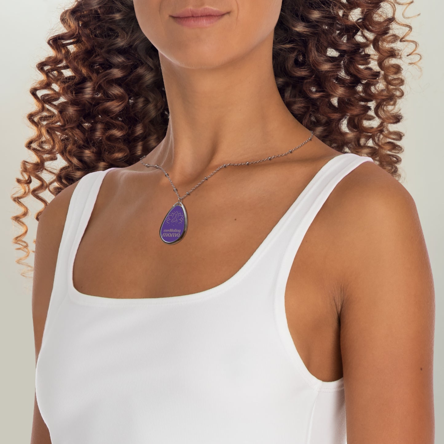 This delicate silver necklace from the Gifts for Mom store showcases a teardrop-shaped pendant with a purple background. It features a simple line drawing of a person meditating, and the words meditating mama beneath it, perfect for the love of meditation.