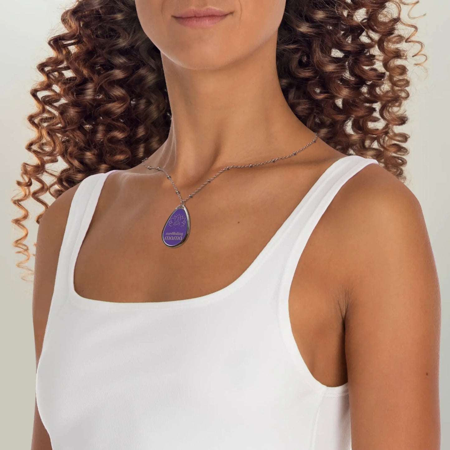 This delicate silver necklace from the Gifts for Mom store showcases a teardrop-shaped pendant with a purple background. It features a simple line drawing of a person meditating, and the words meditating mama beneath it, perfect for the love of meditation.