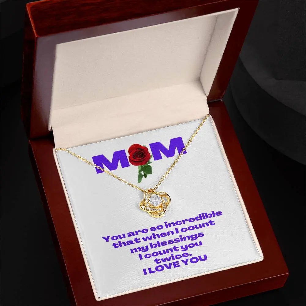 A yellow gold heart-shaped necklace rests in a wooden jewelry box from the Gifts for Mom store. The inner lid features MOM with a red rose design. Below, a heartfelt message reads, You are so incredible that when I count my blessings, I count you twice. I LOVE YOU.