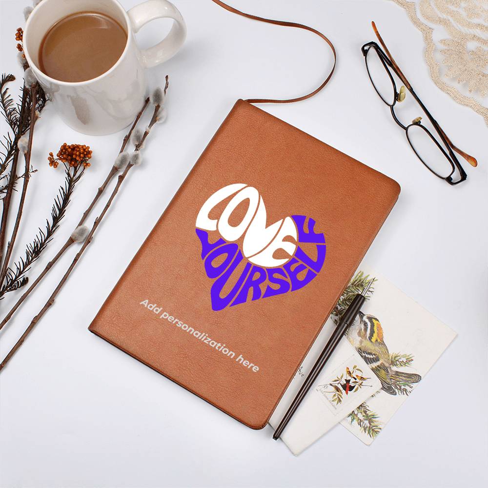 A vegan leather journal featuring an engraved heart made up of the word "love" in white and "yourself" in purple. This journal from the Gifts For Mom store is personalizable.