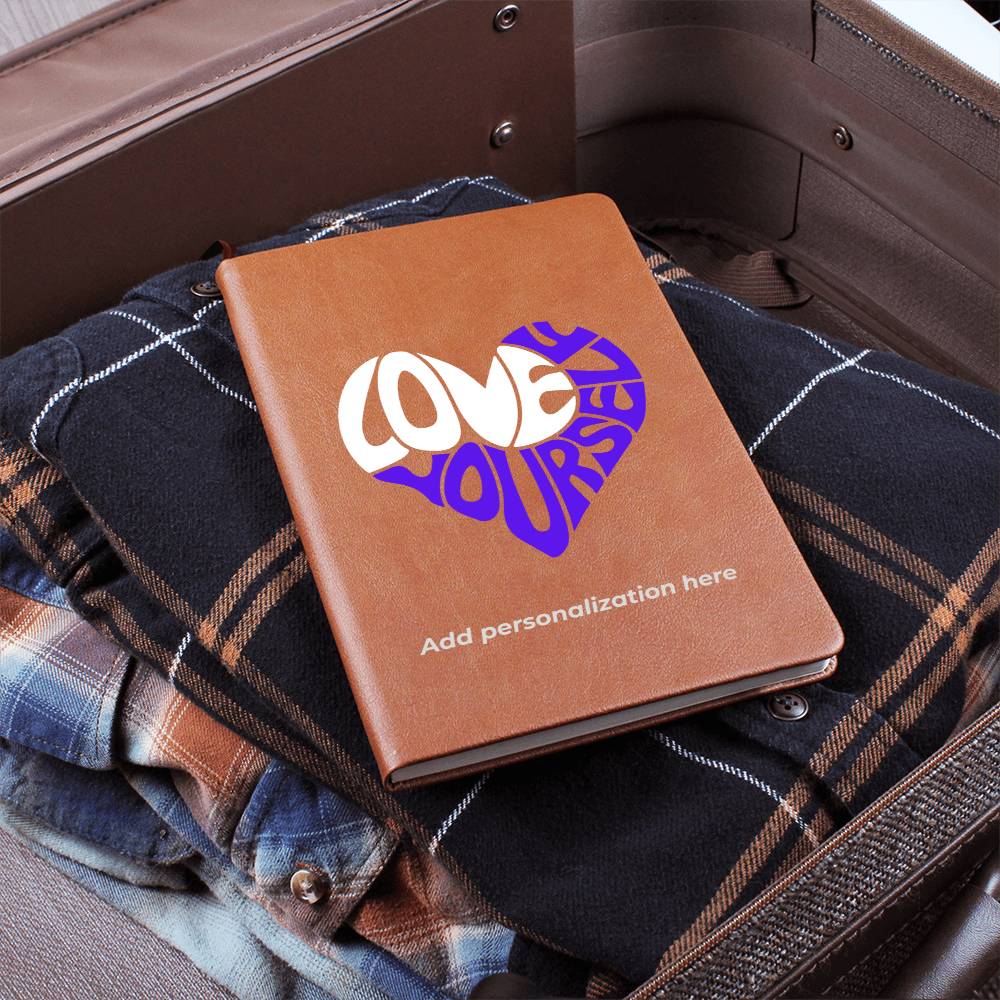 A vegan leather journal featuring an engraved heart made up of the word "love" in white and "yourself" in purple. This journal from the Gifts For Mom store is personalizable.