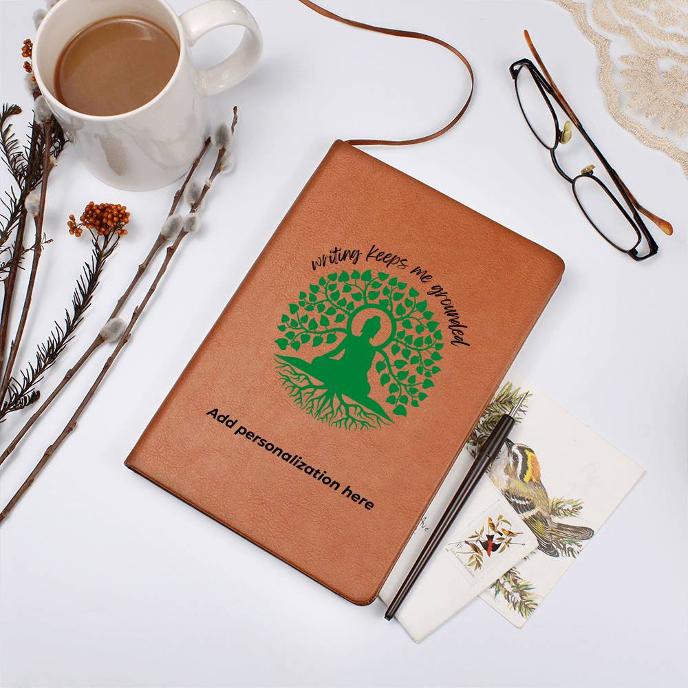 A vegan leather journal featuring an engraved green tree, roots, and a person design beautifully displays the phrase writing keeps me grounded. This journal from the Gifts For Mom store is personalizable.