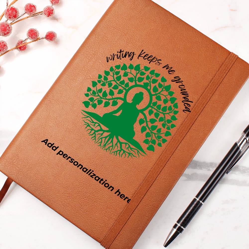 A vegan leather journal featuring an engraved green tree, roots, and a person design beautifully displays the phrase writing keeps me grounded. This journal from the Gifts For Mom store is personalizable.