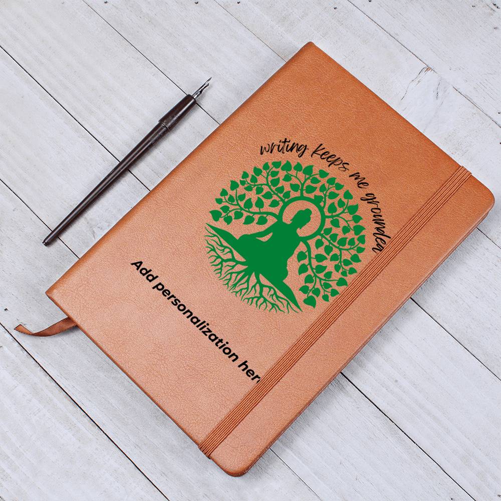 A vegan leather journal featuring an engraved green tree, roots, and a person design beautifully displays the phrase writing keeps me grounded. This journal from the Gifts For Mom store is personalizable.
