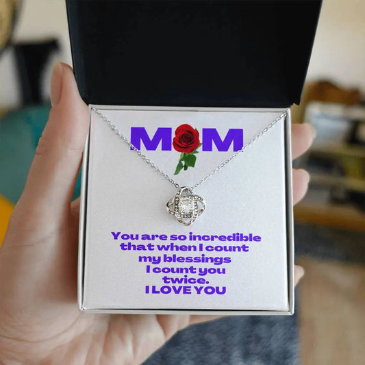 A white gold heart-shaped necklace rests in a box from the Gifts for Mom store. A message card features MOM with a red rose design and a heartfelt message reads, You are so incredible that when I count my blessings, I count you twice. I LOVE YOU.