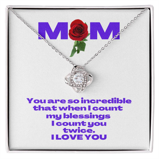 A white gold heart-shaped necklace rests in a box from the Gifts for Mom store. A message card features MOM with a red rose design and a heartfelt message reads, You are so incredible that when I count my blessings, I count you twice. I LOVE YOU.